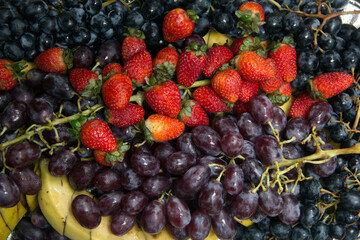 Bunches of grapes, red strawberries and sliced banana, top view. Background of fruit.
