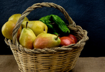 organic fruits and vegetables on a cane basket on rustic bacground