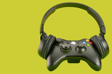 Video game controller using a headset on a green background surface, selective focus.