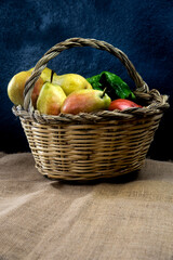 organic fruits and vegetables on a cane basket on rustic bacground