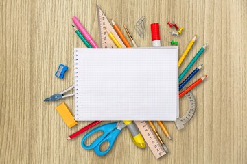 An assortment of colored school supplies and blank notebook on the desk