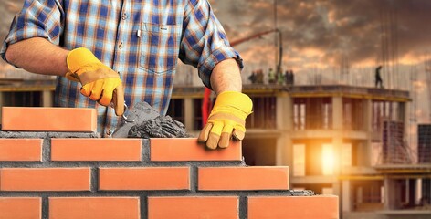 Bricklayer worker installing brick masonry - obrazy, fototapety, plakaty