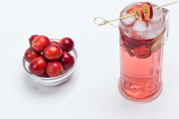 Homemade refreshing summer apple drink with ice in glass. Sliced apples on stick. Small red apples in glass cup