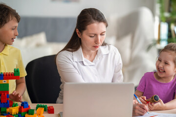 Young women works at home with laptop, along with children. Children make noise.