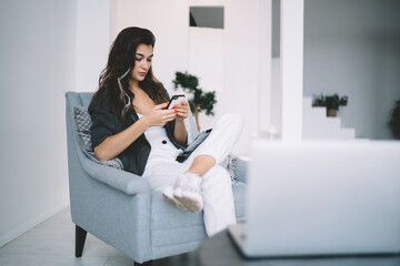 Young brunette with long hair browsing mobile phone at home