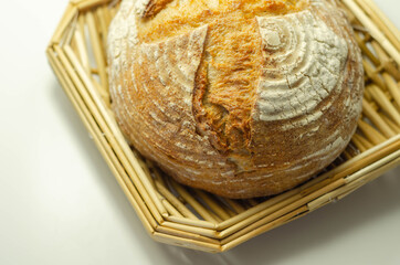 Traditional round loaf of bread baked according to a classic recipe, served on a wicker tray