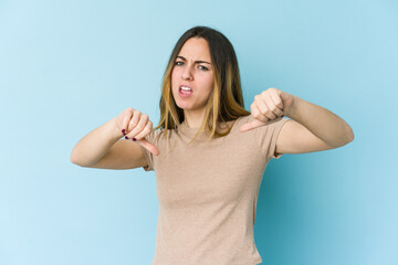 Fototapeta premium Young caucasian woman isolated on blue background showing thumb down and expressing dislike.