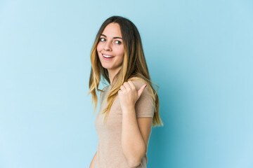 Fototapeta premium Young caucasian woman isolated on blue background points with thumb finger away, laughing and carefree.