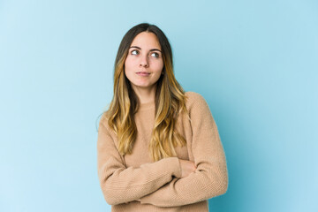 Young caucasian woman isolated on blue background dreaming of achieving goals and purposes
