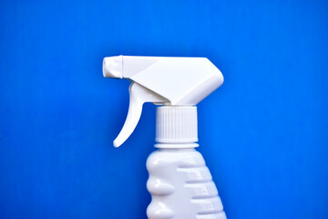 Plastic container with a spray gun in hand on a blue background
