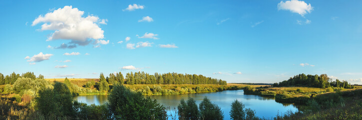 Summer panoramic landscape with calm lake and forest during sunset