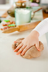child's fingers knead the dough for gingerbread