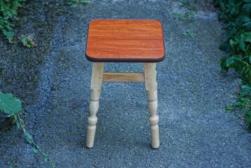 one brown empty wooden stool stands on gray asphalt in the street