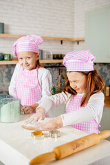 two girls in the kitchen knead gingerbread dough.