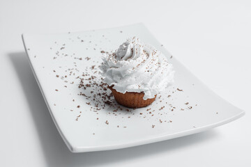 closeup tasty cupcake with whipped cream on plate on white background
