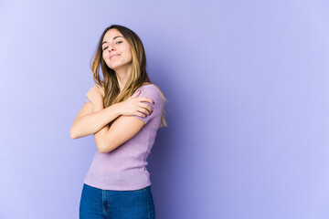 Young caucasian woman isolated on purple background hugs, smiling carefree and happy.
