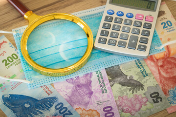 Argentinian currency, paper notes, new animal designs, magnifier, calculator and anti-virus mask. The concept of economics in the era of coronavirus