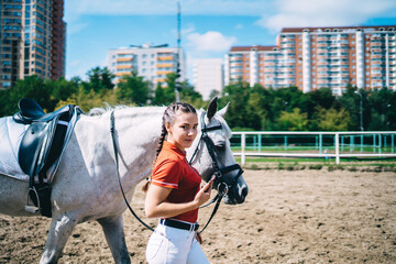 Young woman leading horse on hippodrome