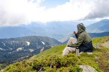 Naklejka na ściany i meble Young woman hiker stand in beautiful mountains on hiking trip. Active tourist resting outdoors in nature. Backpacker camping outside recreation active