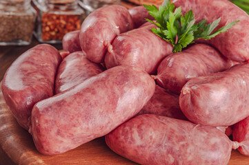 Raw brazilian sausages on the wooden board with ingredients - Linguiça toscana