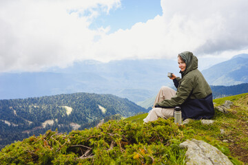 Young woman hiker stand in beautiful mountains on hiking trip. Active tourist resting outdoors in  nature. Backpacker camping outside recreation active