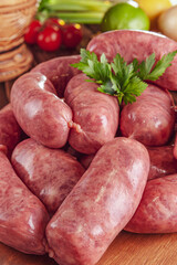 Raw brazilian sausages on the wooden board with ingredients - Linguiça toscana