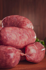 Raw brazilian sausages on the wooden board with ingredients - Linguiça toscana