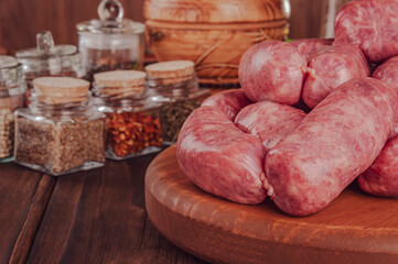 Raw brazilian sausages on the wooden board with ingredients - Linguiça toscana