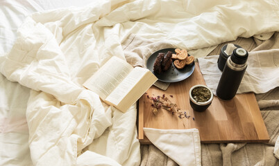 Desayuno argentino con mate y leyendo un libro en la cama, habitación luminosa y clara