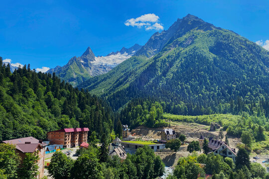 Caucasus Mountains over houses of Dombay resort village in Teberda Nature Reserve in Karachay-Cherkessia region of Russia