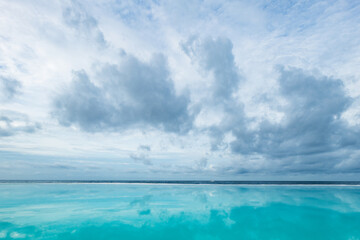 Fototapeta na wymiar Endless pool, small sea stripe and big blue cloudy sky