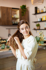cute girl inside the house braids her hair