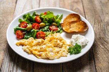 Delicious breakfast - scrambled eggs with fried sausages, cottage cheese and vegetables served on...