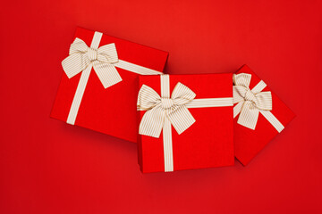Red gift boxes on red background. Gift boxes tied with gold ribbon and bows on red background. Top view. Concept of holidays and greeting cards