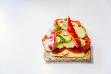 Open faced sandwich isolated on white background. Vegetarian sandwich with cheese, tomatoes, cucumber, radish, and red bell pepper