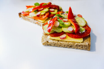 Open faced sandwich isolated on white background. Vegetarian sandwich with cheese, tomatoes, cucumber, radish, and red bell pepper