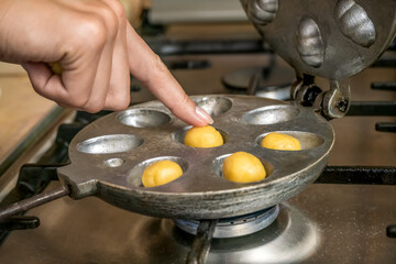 woman's hand puts cookie dough balls in a round cookie baking dish Nut on a gas stove