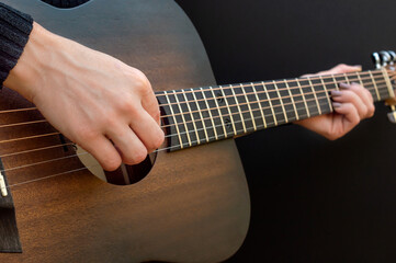Woman playing on acoustic guitar. Close up.