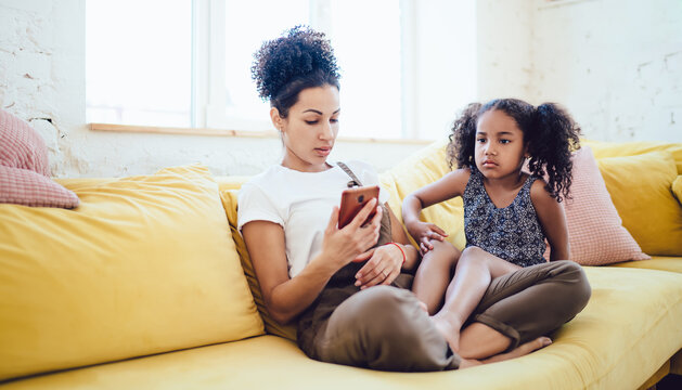 Mother and thoughtful daughter sitting on sofa