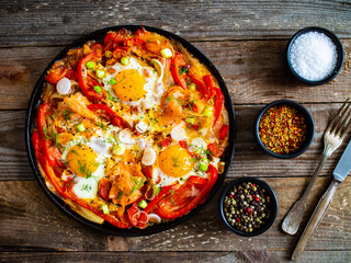 Shakshuka - fried eggs with salmon and vegetables in frying pan

