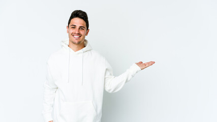 Young caucasian man isolated on white background showing a copy space on a palm and holding another hand on waist.