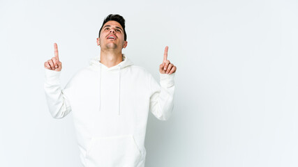 Young caucasian man isolated on white background pointing upside with opened mouth.