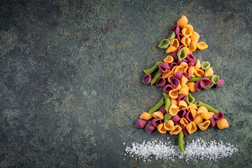 Christmas tree made of raw colored pasta on a stone background. Christmas concept.