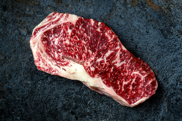 Raw Wagyu beef striploin steak on stone table. Japanese marbled meat, top view
