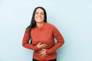 Young caucasian woman isolated on a blue background laughs happily and has fun keeping hands on...