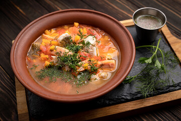 Ukha royally, fish soup, from several varieties of fish, in a clay plate, on a wooden board