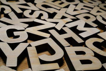 Random wooden block letters lying on wooden surface.