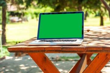 View on a laptop pc with a green screen on a table in the garden