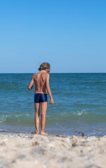 Fototapeta na wymiar happy boy walks into the sea, vertical format