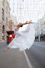 Dancer in white clothes jumps in the city